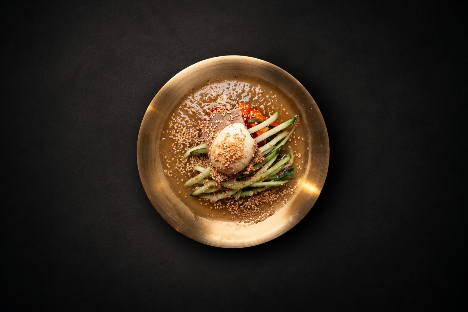A golden bowl of noodles with cucumber and egg