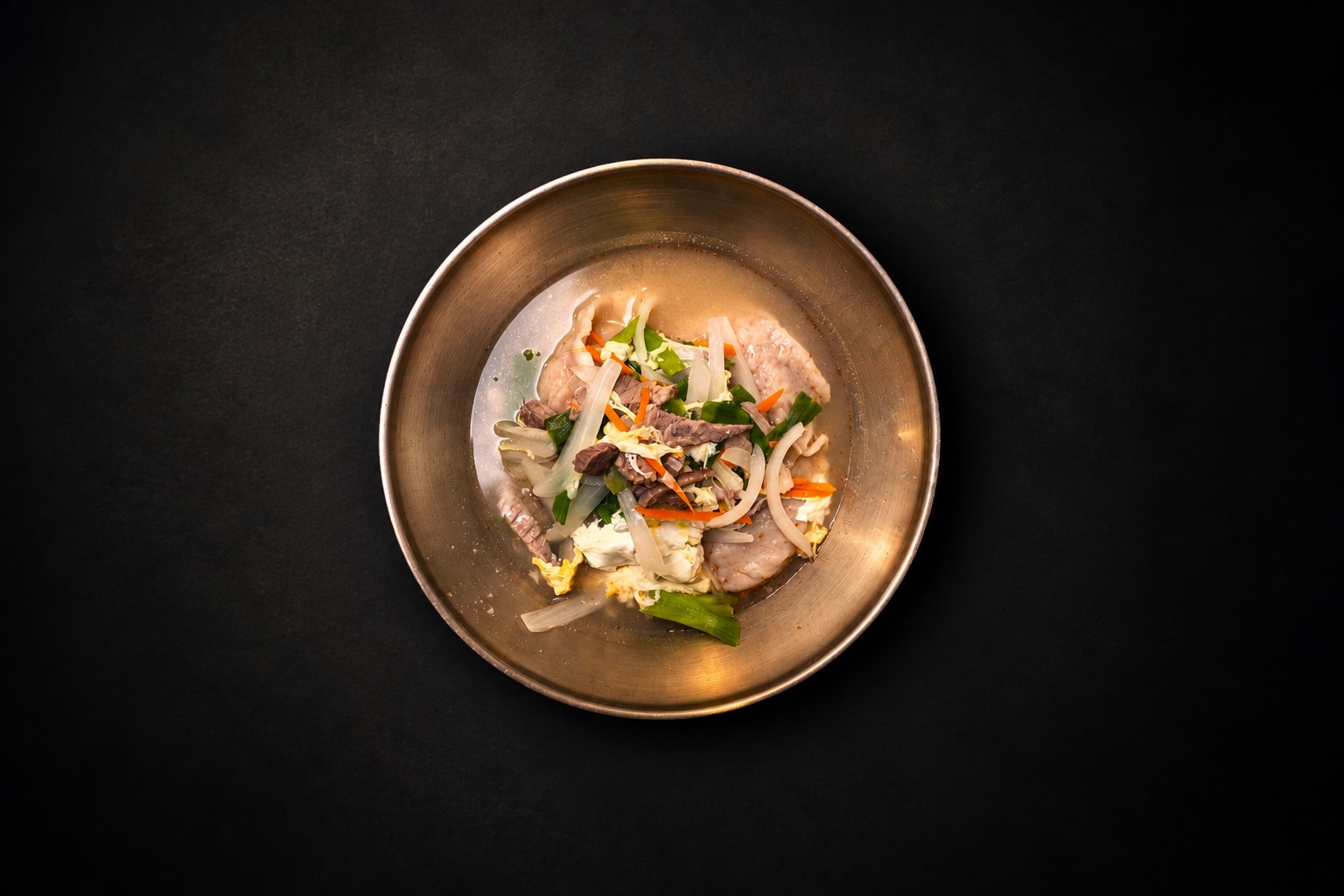 Dumplings, meat, and vegetables in a golden bowl