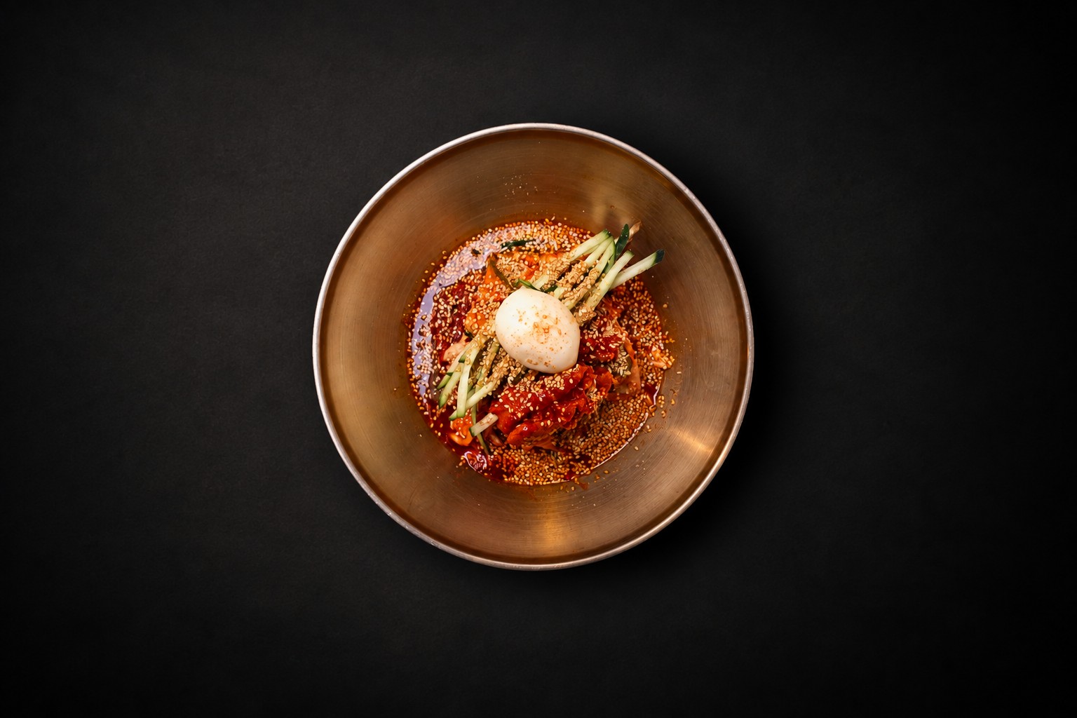 Red noodles, cucumber, and egg in a golden bowl