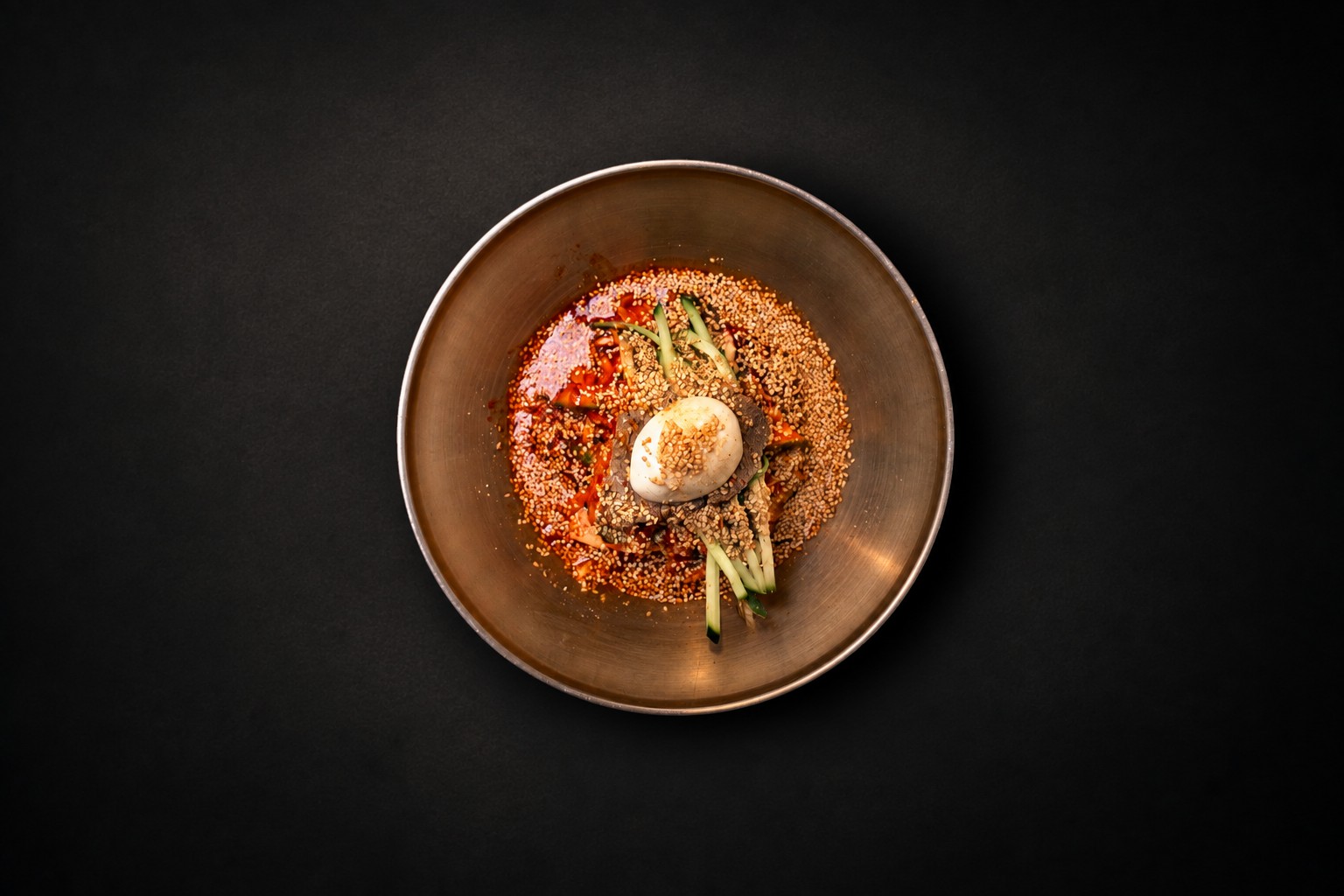 A bowl of red noodles topped with a halved egg
